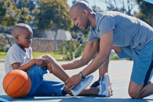 A dad helping his son with an injury on a basketball court