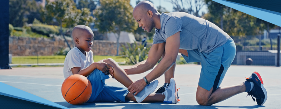 A dad helping his son with an injury on a basketball court